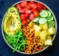 Buddha bowl dish with cucumbers, avocado, pineapple, cherry tomatoes, roasted chickpeas, fresh lettuce salad