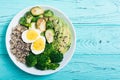 Buddha bowl with quinoa eggs , avocado , brussels sprouts and broccoli . Food vegan salad on wooden backgground