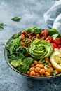 Buddha bowl salad with baked sweet potatoes, chickpeas, broccoli, tomatoes, greens, avocado, pea sprouts on light blue background Royalty Free Stock Photo
