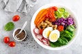 Buddha bowl salad with chickpeas, sweet pepper, tomato, cucumber, red cabbage kale, fresh radish, spinach leaves and boiled egg