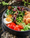 Buddha bowl salad with shrimps, arugula, spinach, avocado, tomatoes, green edamame beans, eggs on marble background. Healthy salad Royalty Free Stock Photo