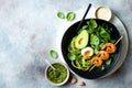 Buddha bowl with soft boiled egg, avocado, greens, zucchini noodles, grilled shrimps and pesto sauce. Low carb lunch bowl Royalty Free Stock Photo