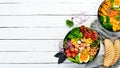 Buddha bowl: vegetables, fruits and meat in black plate on old background. Autumn dishes. Top view.
