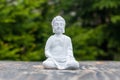 Buddha - ceramic statuette budha on green background. Buddhism, meditation and yoga concept