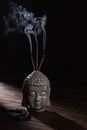 Buddha head with burning incense sticks Royalty Free Stock Photo