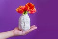 Buddha head with gred tulips in man`s hand Royalty Free Stock Photo