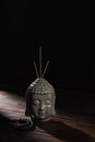 Buddha head with incense sticks on wooden table Royalty Free Stock Photo