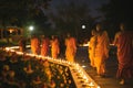 Buddha Purnima concept - monks and laypeople light candles and walk around a stupa