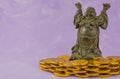 Buddha sculpture with gold coin donations on pink background Royalty Free Stock Photo