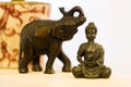 Buddha sitting in lotus position next to an elephant