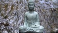 Buddha statue on the background of a waterfall, water flows over the stone. Slow playback speed - 50%.