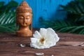 Buddha statue with beautiful fresh white flowers green leaves on wooden background. Concept of harmony, balance and meditation, Royalty Free Stock Photo