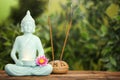 Buddha statue with burning candle and lotus flower near incense sticks on wooden table. Space for text Royalty Free Stock Photo