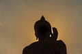 Buddha statue with dark silhouette with golden sunlight in eveni