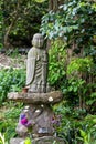 Statue of Jizo, enlightened monk who is the protector of the dead children in Japan. Buddha statue with flower decoration