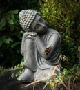 Buddha statue in the garden with a butterfly on his arm.