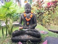 Buddha statue with garlands and offerings at its foot Royalty Free Stock Photo