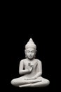 Buddha statue seated in light grey stone against a black background, copy space