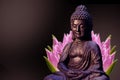 Buddha statue sitting in meditation pose against deep dark background and pink lotus flower behind. Royalty Free Stock Photo