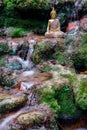 Buddha statue sitting in a river with rocks and green moss Royalty Free Stock Photo