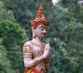 Buddha statue stands in a peaceful woodland setting at Thai Temple surrounded by tall trees