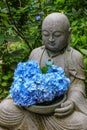 A buddha statue at a temple, holding fresh hydrangea flowers