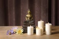 Buddha Statue on the wooden table with burning candles and colorful flowers. Royalty Free Stock Photo