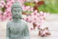 Buddha statuette against blurred blooming sakura branch as background with copy space Royalty Free Stock Photo