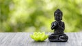 A Buddha statuette and a lotus candle on a wooden board Royalty Free Stock Photo