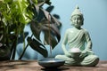 Buddhism religion. Decorative Buddha statue with burning candle, incense stick on wooden table and monstera against light blue Royalty Free Stock Photo