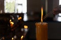 Buddhist Lent concept. Women hand lighning the incense from big candles in the Buddhist temple Close up light form candles.