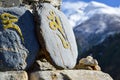 A Buddhist mani stone or prayer stone on the Annapurna Circuit with the out of focus snow capped Himalayas behind. Nepal.