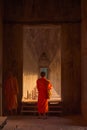 Buddhist monk at Angkor Wat, wearing traditional saffron colored robes, standing on one if the inner galleries. Royalty Free Stock Photo