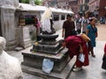 A Buddhist monk bows at a sacred sculpture at the Boudhanath stupa in Kathmandu, Nepal