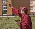 Buddhist monk in burgundy clothes performs ritual. Ivolginsky Datsan, Buryatia. Russia.
