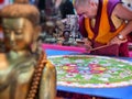 Buddhist monk create drawing mandala with multicolor sands selective focus on hands Royalty Free Stock Photo