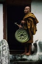 buddhist monk with a gong in front of the entrance of his monastery