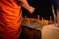 Buddhist monk hands holding candle and lighting up candle in temple