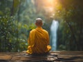 Buddhist monk meditating near a waterfall during a beautiful sunset or sunrise Royalty Free Stock Photo