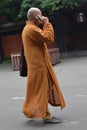 Buddhist monk in orange robe with cell phone in Chengdu, China