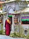 Buddhist monk praying near prayer wheels, Boudhanath, Kathmandu, Nepal Royalty Free Stock Photo