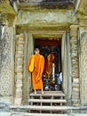 Buddhist monk in saffron robes on the steps of the temple