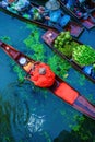 Buddhist monk in small wooden boat rowing in canal to receive food from villagers