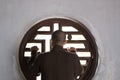 Buddhist monk stands by a round window