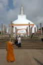 A Buddhist monk takes a photograph of two ladiies standing in front of the magnificent Ruwanwelisiya Dagoba at Anuradhapura.
