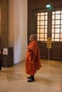 A Buddhist monk in traditional colorful robes stands at the entrance to the Karlskirche church on Karlsplatz.