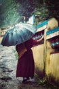 Buddhist monk with umbrella spinning prayer wheels