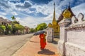 A Buddhist monk walks by the Wat Sen Temple in Luang Prabang, Laos