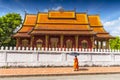 A Buddhist monk walks by the Wat Sen Temple in Luang Prabang, Laos