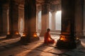 Buddhist monk praying in ancient temple at sunrise with candles Royalty Free Stock Photo